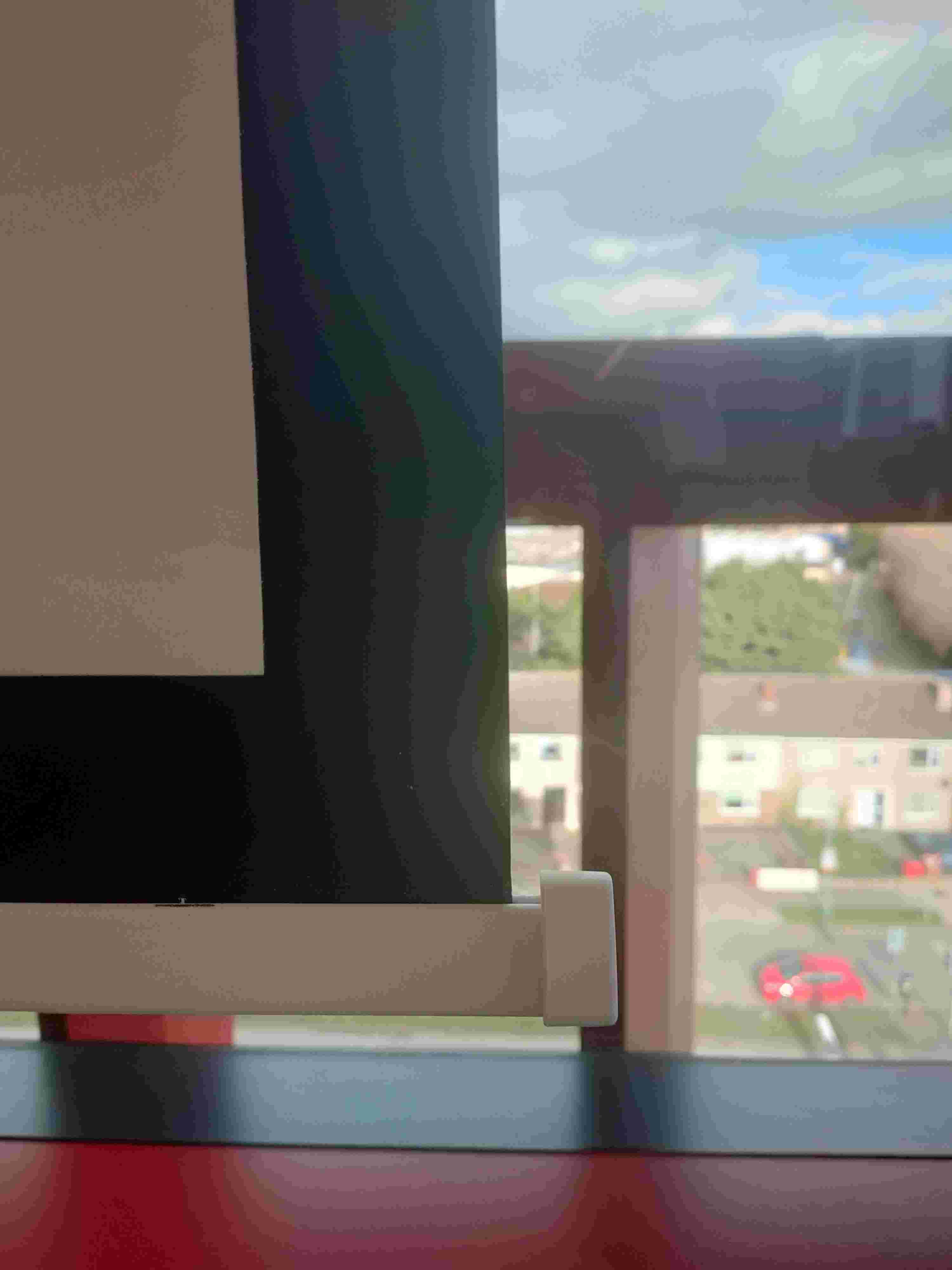 Projector screen hanging in front of a window — the screen's original sharp-cornered end cap was catching on furniture when raised.