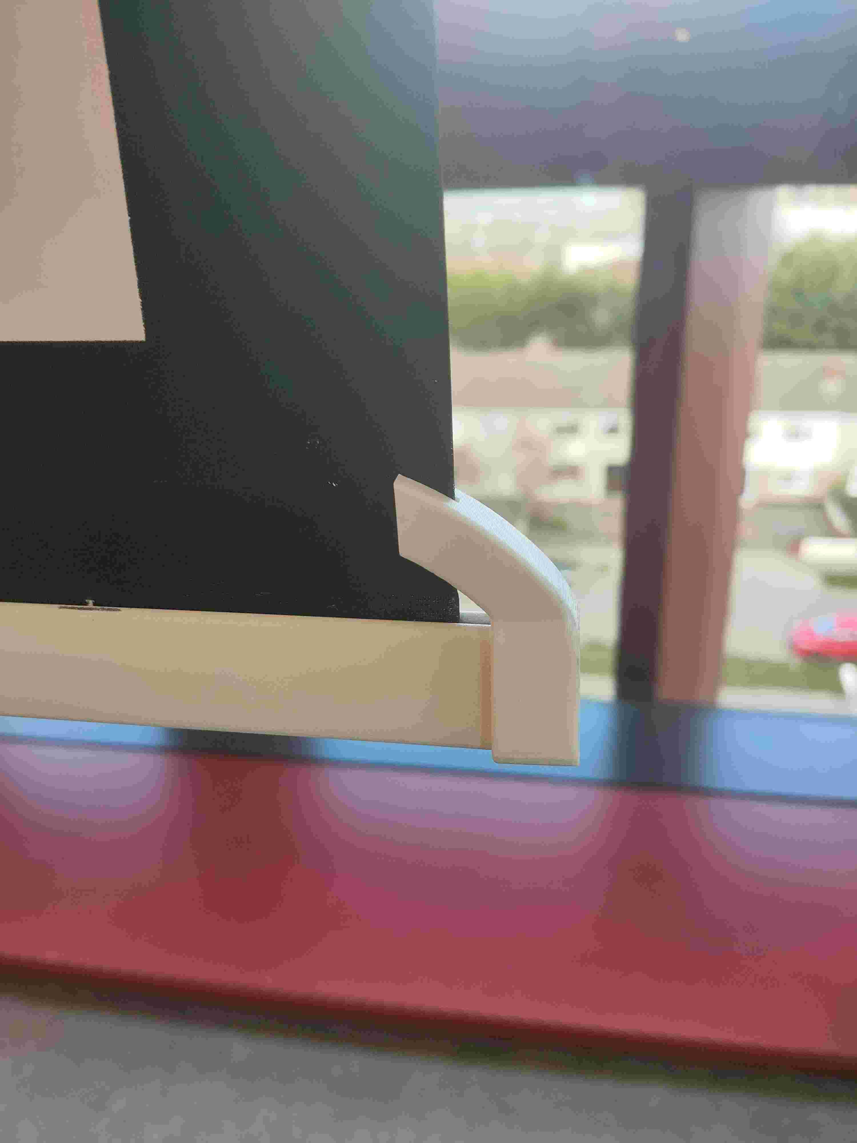 3D-printed curved end bracket snapped over the projector screen rail — the smooth profile slides off furniture instead of catching or tearing.