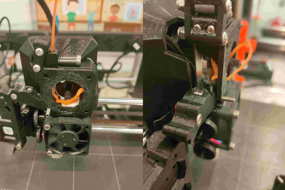 Side view of the extruder assembly showing orange filament tangled around the drive gear and tension arm during a feed jam.